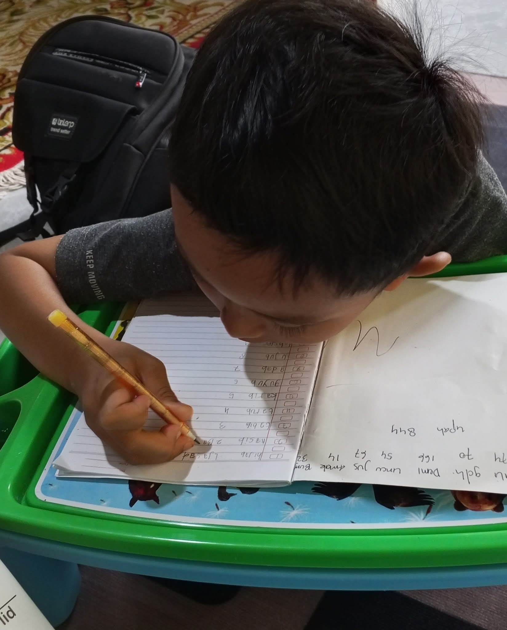 Anak sedang latihan menulis di buku