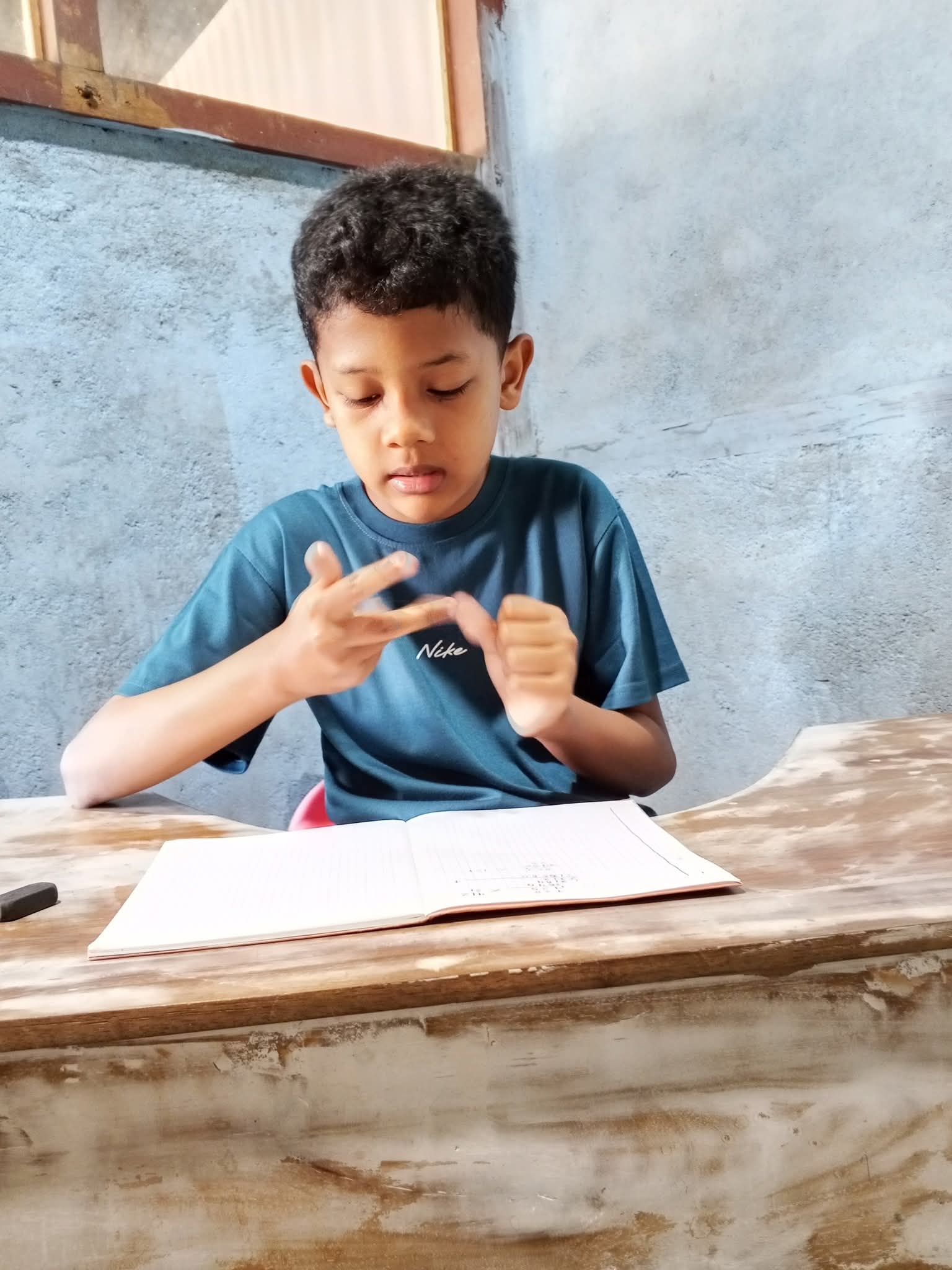 Anak sedang belajar menghitung dengan buku tulis